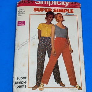 May include: A vintage Simplicity sewing pattern envelope featuring two women modeling pants. The envelope has text that reads "SUPER SIMPLE" and "pants". The size is listed as 8, with a waist of 23 inches and hips of 33.5 inches. The background is blue.