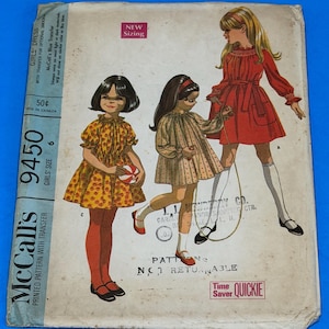 May include: Vintage McCall's sewing pattern for girls' dresses, size 6. The cover features illustrations of three girls in dresses, with text including "New Sizing" and "Quickie Time Saver". The pattern includes a transfer.