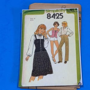 May include: A vintage Simplicity sewing pattern, size 12 Misses, featuring illustrations of women's clothing designs. The pattern packet is primarily green and white, with a black and white dotted dress design on the front.