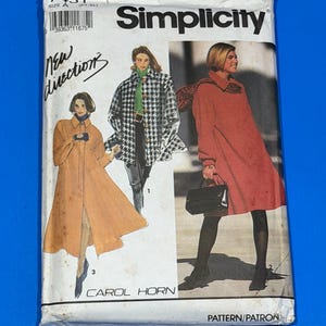 Könnte beinhalten: Ein Vintage-Simplicity-Schnittmuster, Größe A, mit Illustrationen von Damenmänteln und einem Kleid. Die Schnittmusterpackung ist weiß mit dem Simplicity-Logo, dem Text "New Directions" und "Carol Horn".