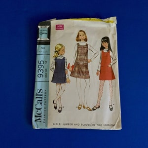 May include: Vintage McCall's sewing pattern 9395 for girls' jumpers and blouses. The pattern features illustrations of three girls wearing different jumper and blouse styles. The pattern is marked "New Sizing" and includes the price of 50¢.