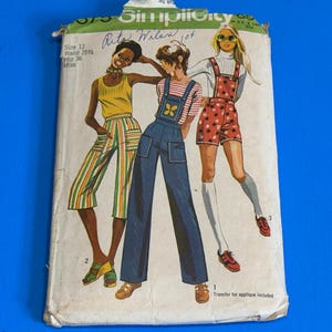 May include: Vintage Simplicity sewing pattern featuring three illustrated figures in 1970s fashion. The pattern includes a jumpsuit, shorts, and striped pants. The pattern is size 12, with a 25.25-inch waist and a 36-inch hip. The text "Rita Wilan" is visible.