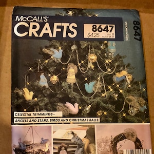 May include: A vintage McCall's Crafts pattern book, featuring a Christmas tree decorated with celestial trimmings. The cover displays the text "McCall's Crafts" and the number "8647". The cover also shows angels, stars, birds, and Christmas balls.