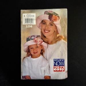May include: A vintage sewing pattern package featuring a woman and a child wearing matching pink hats adorned with flowers. The package has the text "SEE & SEW NOW YES! IT'S EASY" and the number "3298".