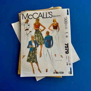 May include: A vintage McCall's sewing pattern, featuring illustrations of women's clothing designs. The pattern packet displays a variety of outfits, including skirts, pants, and jackets. The pattern number is 7579, and the bust size is 38 inches.