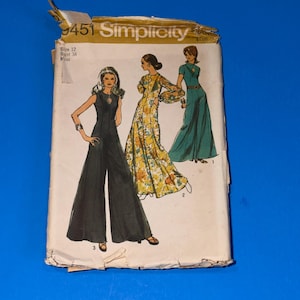 Pode incluir: Padrão de costura Simplicity vintage com ilustrações de três macacões diferentes. O padrão é rotulado "9451 Simplicity" com tamanho 12 e busto 86 cm. A capa está ligeiramente desgastada sobre um fundo azul.