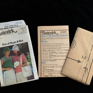 May include: A vintage Butterick sewing pattern for a trio of bags and a hat. The pattern packet features an image of two women wearing the bags and hats. Also included are instructions and pattern pieces.