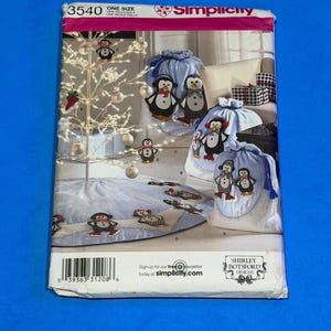 May include: Simplicity sewing pattern featuring penguin designs. The pattern includes instructions for making a tree skirt and drawstring bags. The packaging is white and blue with the Simplicity logo and the number 3540.