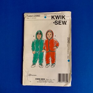 May include: A vintage Kwik-Sew sewing pattern, pattern number 2260, featuring illustrations of children's hooded outfits in green and red. The pattern includes sizes T1-T2-T3-T4. The cover is white with the Kwik-Sew logo and text.