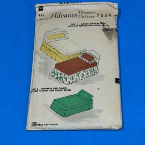 May include: An Advance Decorator Pattern 7534 envelope featuring illustrations of bedding sets. The graphics show a bed with a yellow ruffled coverlet, a bed with a brown top and floral flounce, and a green bedspread with a matching pillow.