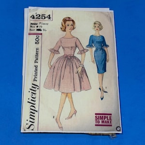 May include: A vintage Simplicity sewing pattern envelope 4254 for a junior misses dress. The cover features illustrations of two dress styles: a pink gingham dress with ruffled sleeves and a blue sheath dress with a tie waist. Text includes 4254, 50c, and Simple to Make.