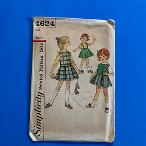 May include: Vintage Simplicity pattern 4624 for a child's dress, size 3. The pattern features illustrations of young girls in plaid dresses and a green dress. The pattern is printed on aged paper with a blue background.