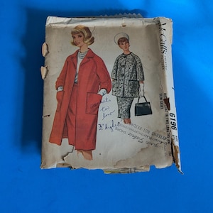 May include: A vintage McCall's 6196 sewing pattern envelope featuring illustrations of two coat and skirt outfits. The paper envelope is worn and stained, with handwritten ink notes stating pockets too low and 3 inches higher.