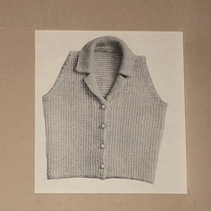 Puede incluir: Un chaleco de punto gris claro con cuello y cierre de botones en la parte delantera. El chaleco presenta un patrón de punto texturizado y un diseño clásico. La imagen es una toma de cerca de la prenda.