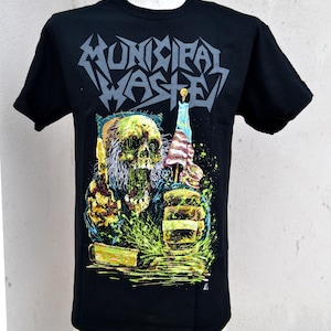 May include: Black t-shirt featuring the band name "MUNICIPAL WASTE" in gray, stylized lettering. The graphic depicts a zombie-like figure holding a candle with an American flag design. The design includes green and yellow accents.