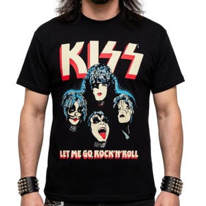 Può includere: T-shirt nero con il logo della band KISS in rosso e bianco. La maglietta mostra i volti dei membri della band con trucco blu, bianco e rosso. Il testo "LET ME GO, ROCK'N'ROLL" è stampato sotto.