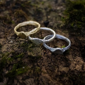 Könnte beinhalten: Drei Ringe, die übereinander gestapelt sind. Der obere Ring ist silber, der mittlere Ring ist silber und der untere Ring ist gold.