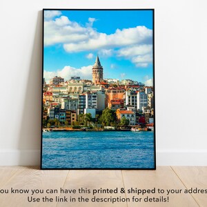 May include: A framed photograph of a cityscape with a tall tower in the center. The city is on a waterfront with blue water and a cloudy sky.