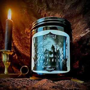 May include: A brown glass candle jar with a black and white label featuring a spooky house in the woods. The label reads "Forest & Folklore" and "Haunted".