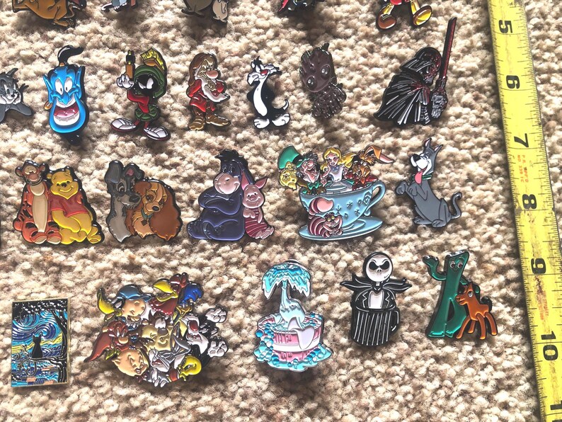 May include: A collection of enamel pins featuring various cartoon characters, including Mickey Mouse, Winnie the Pooh, and the Grinch. The pins are colorful and detailed, and they would make a great addition to any fan's collection.