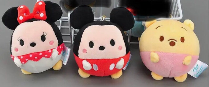 Pode incluir: Tr&ecirc;s brinquedos de pel&uacute;cia redondos, Mickey Mouse, Minnie Mouse e Winnie the Pooh, t&ecirc;m olhos grandes. Mickey Mouse est&aacute; vestindo uma camisa vermelha com bolinhas brancas. Minnie Mouse est&aacute; vestindo um vestido vermelho com bolinhas brancas e um la&ccedil;o vermelho. Winnie the Pooh est&aacute; vestindo uma camisa rosa.