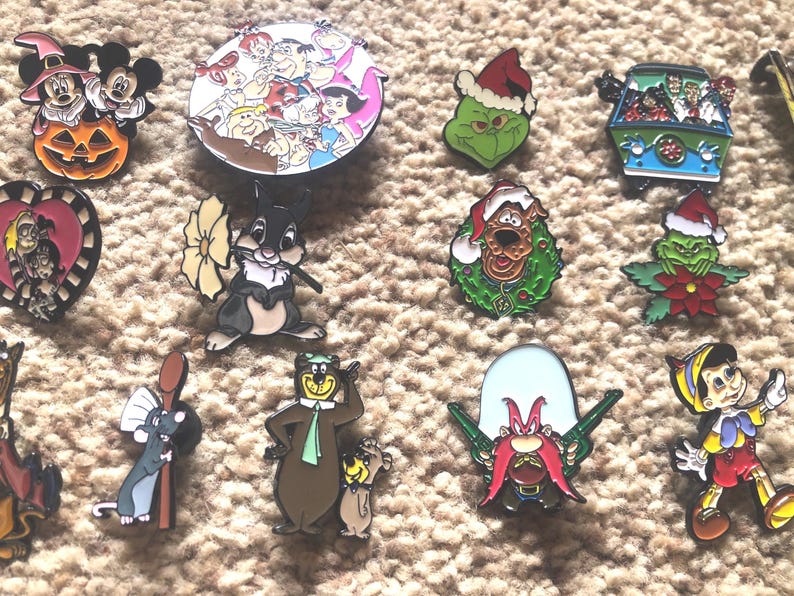 May include: A collection of 14 colorful enamel pins featuring various cartoon characters, including Mickey Mouse, Bugs Bunny, and the Grinch. The pins are all different sizes and shapes, and they are perfect for adding a touch of whimsy to any outfit or bag.