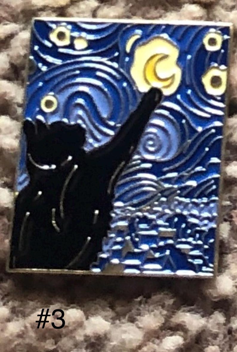 May include: A black cat silhouette reaching up towards a yellow crescent moon in a blue and white starry night sky. The image is a pin with a silver border.