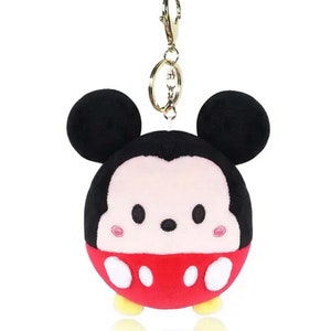 Pode incluir: Um chaveiro de pel&uacute;cia do Mickey Mouse com uma roupa vermelha e branca e orelhas pretas. O chaveiro tem um anel de metal dourado.
