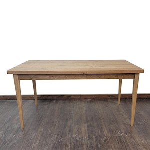 May include: A light wood dining table with a rectangular top and four legs. The table is made of solid wood and has a natural finish.