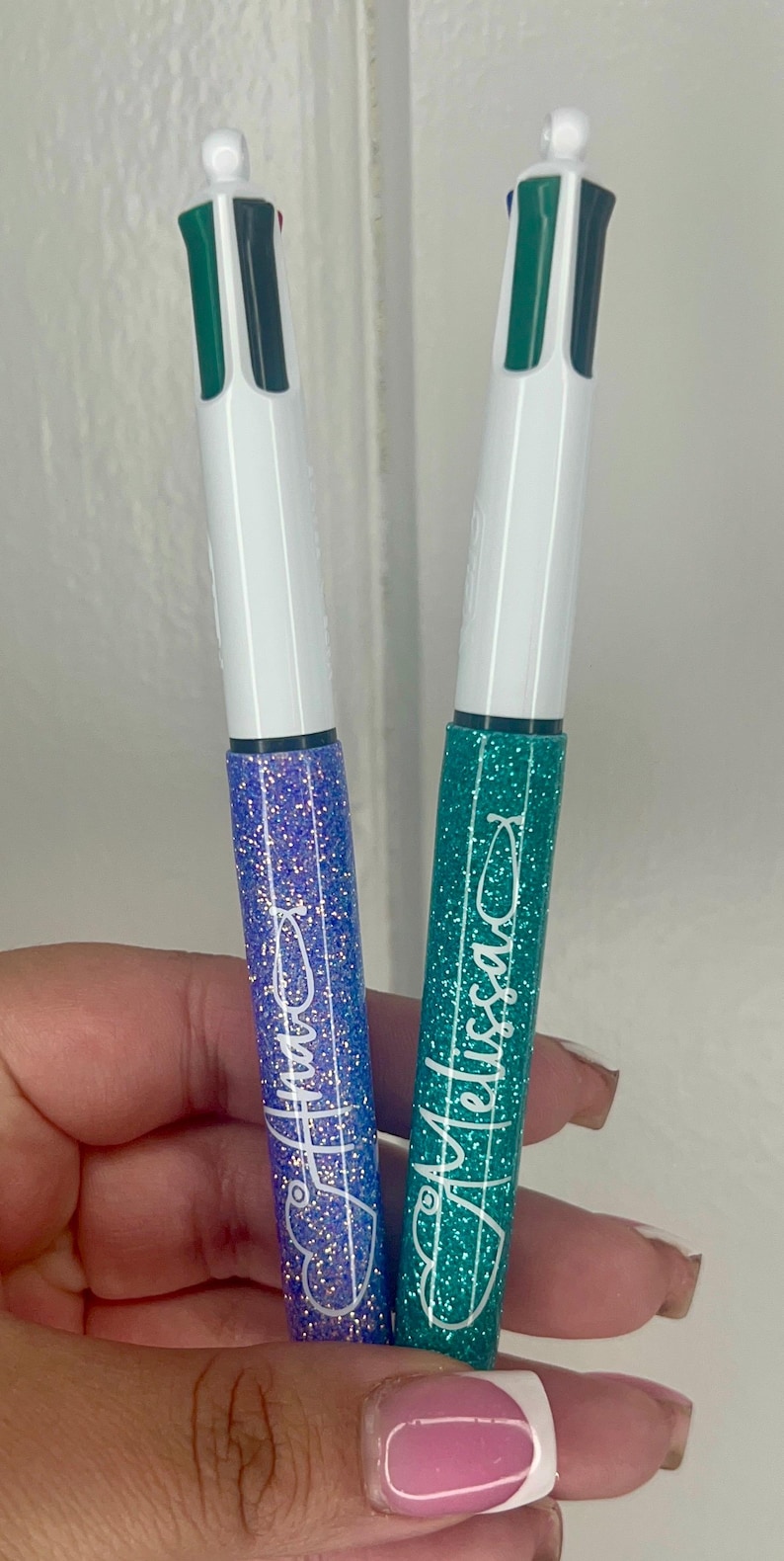 May include: Two glitter pens with personalized names, one blue and one green. The pens have multiple ink colors.