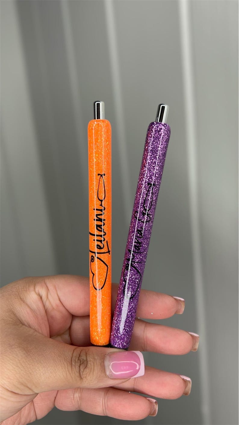 May include: Two glitter pens with personalized names. The orange pen says "Jellani" and the purple pen says "Mama Kay".