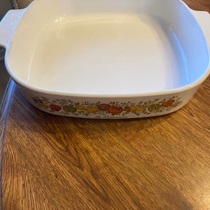 May include: White rectangular baking dish with rounded corners and handles. The dish features a decorative border with colorful illustrations of vegetables and the text "Le Romarin".