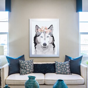May include: A white couch with blue throw pillows in a living room setting. A framed print of a wolf wearing a flower crown hangs on the wall above the couch.