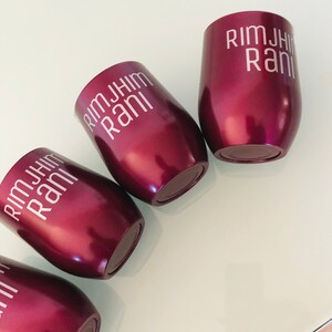 May include: Four burgundy-colored stainless steel tumblers with the text "Rimjhim Rani" printed in white on each.
