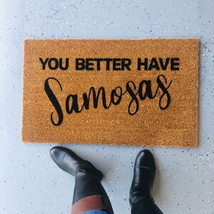 Puede incluir: Una alfombra de bienvenida marr&oacute;n con el texto "You better have samosas" en letras negras.