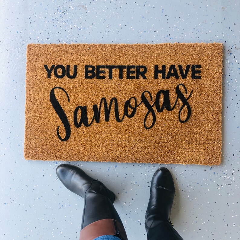 Puede incluir: Una alfombra de bienvenida marr&oacute;n con el texto "You better have samosas" en letras negras.