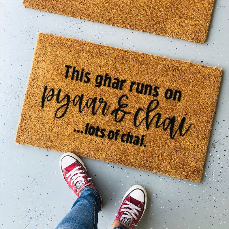 Puede incluir: Una alfombra de coco marr&oacute;n con el texto "This ghar runs on pyaar & chai...lots of chai."
