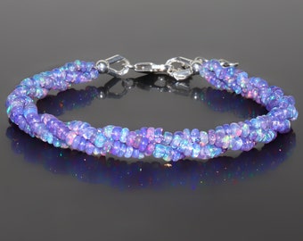 May include: A silver bracelet with a twisted design made of small, iridescent purple opal beads.