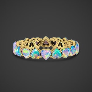 May include: A gold band ring featuring a row of iridescent heart-shaped opal stones.