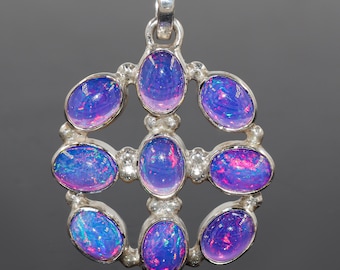 May include: A silver pendant with a circular design featuring eight oval-shaped opal stones. The opals are a vibrant purple with hints of pink and blue.