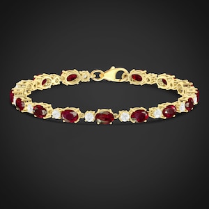 Peut inclure: Un bracelet en or avec des rubis rouges ovales et de petits diamants sertis en ligne continue.
