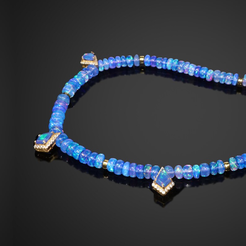 May include: A blue opal necklace with three larger opal pendants set in gold. The necklace is made of small blue opal beads and gold beads.