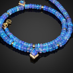 May include: A double strand necklace made of blue opal beads with a gold pendant featuring a blue opal gemstone surrounded by small diamonds.