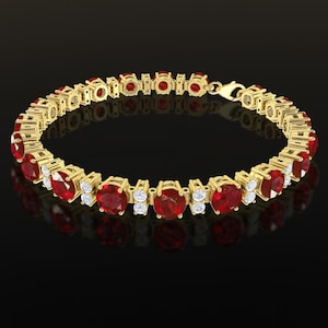 May include: A gold bracelet featuring oval-cut red gemstones and small white gemstones. The bracelet is set in a gold metal and has a clasp closure. The gemstones are evenly spaced along the bracelet's length.