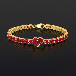Peut inclure: Un bracelet en or avec un cœur en rubis au centre et des rubis de forme ovale. Le bracelet est doté d'une fermeture à fermoir. Fond noir.