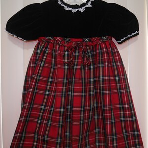 This is a classic Red plaid dress with the sleeves and upper chest of dressing Black Velvet with white lace trim around crew neckline and short puffed sleeves. A very classic child's formal dress for any special occasion.