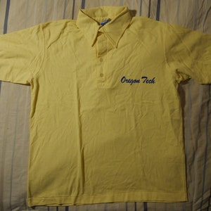 May include: A yellow short-sleeved polo shirt with a blue embroidered logo that says "Oregon Tech".