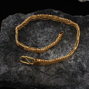 May include: A gold chain bracelet with a box chain design. The bracelet has a lobster clasp closure.