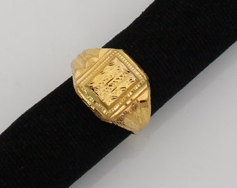 May include: A gold signet ring with a square-shaped top and intricate engraved details.