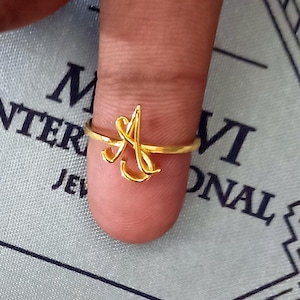May include: A gold ring with the letter "A" in a cursive script design.